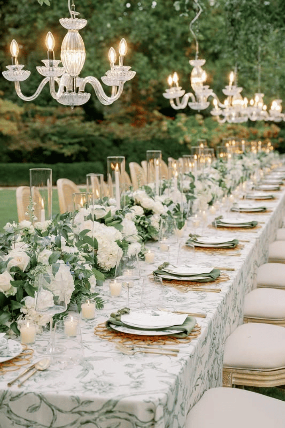 Luxury garden reception table with chandeliers and lush green centerpieces