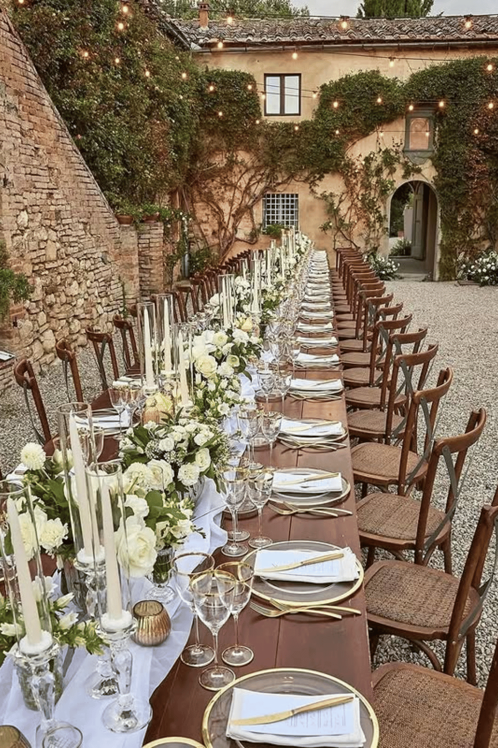 Rustic Italian courtyard table with tall candles and classic white florals