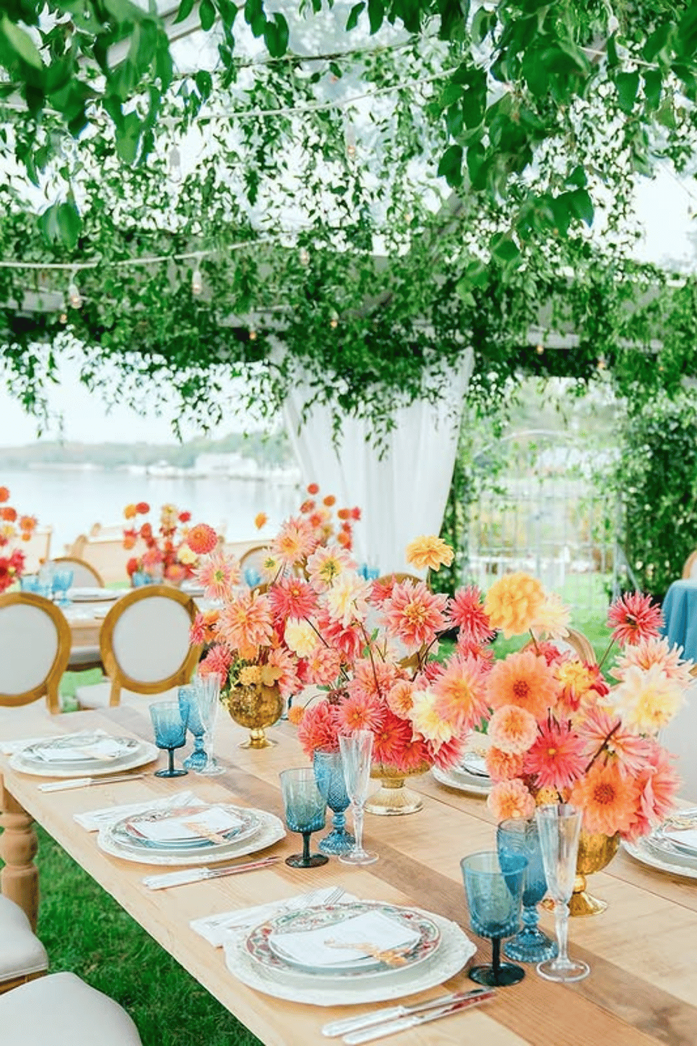 Bright wedding table with bold orange-pink florals and blue glassware. Table Setting Ideas