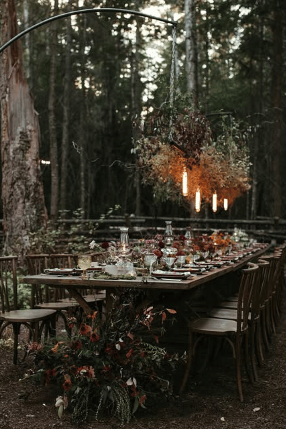 Forest wedding setup with dramatic florals and hanging lights