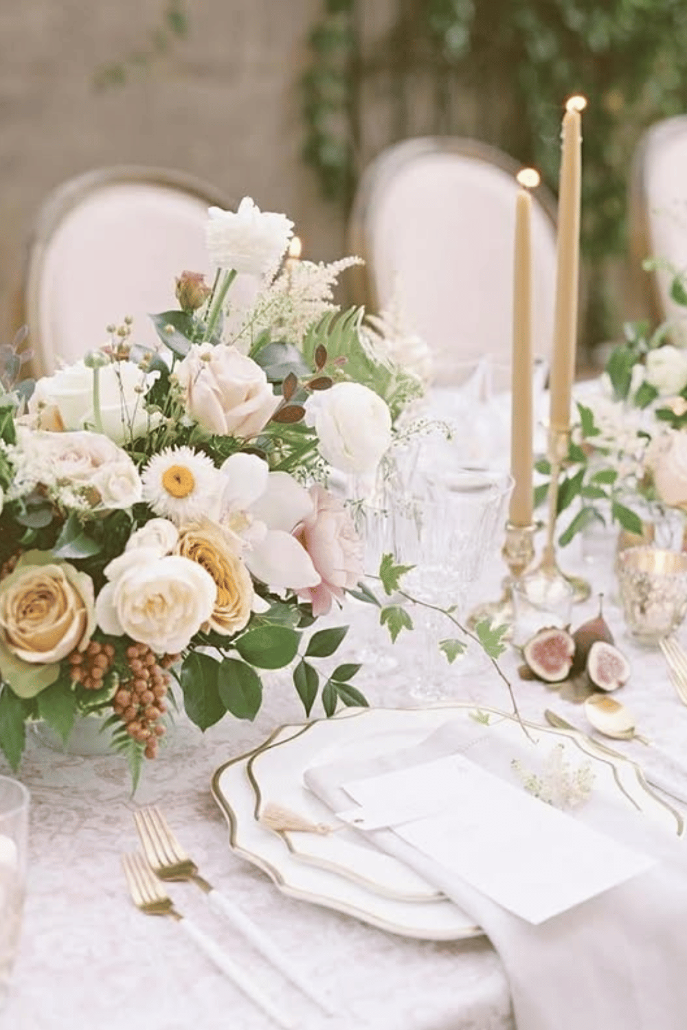 Soft neutral wedding tablescape with cream roses, figs, and gold-rimmed plates