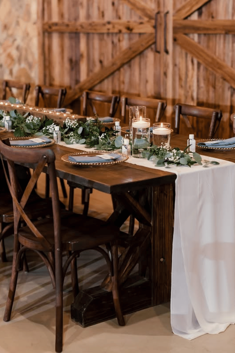 Rustic wooden table with baby's breath runner and glass candle holders