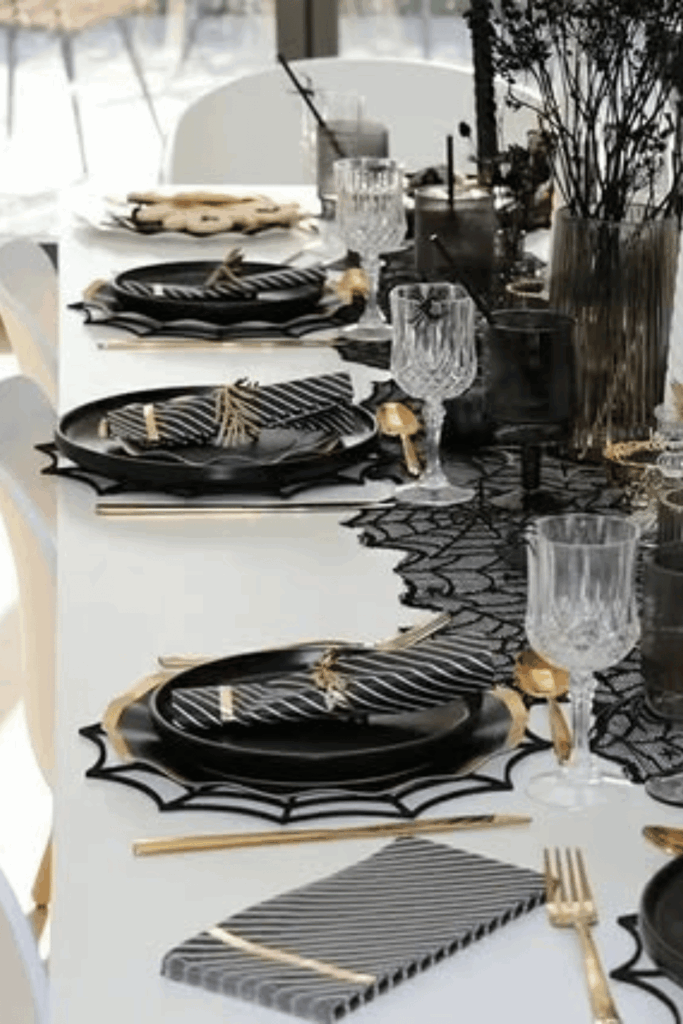 Black and gold Halloween table with spider web placemats and striped napkins