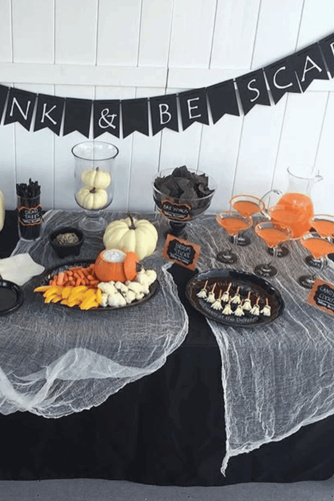Halloween snack and drink table with veggies, dips, and candy