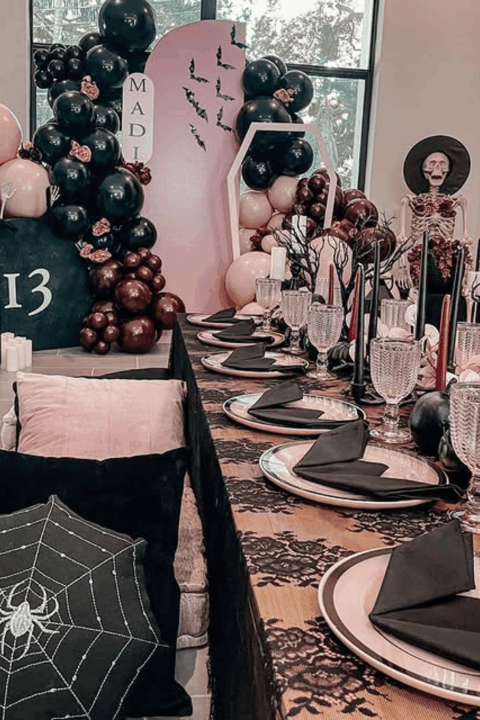 Halloween table with pink and black decor and balloon arch