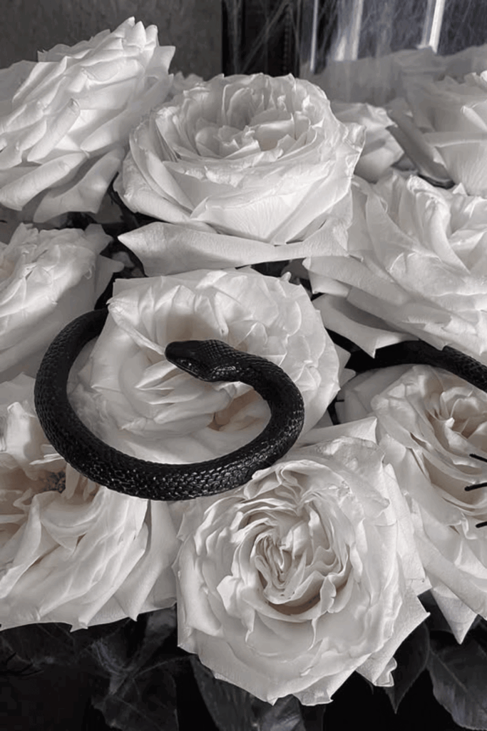 White roses with a black faux snake for a spooky Halloween centerpiece