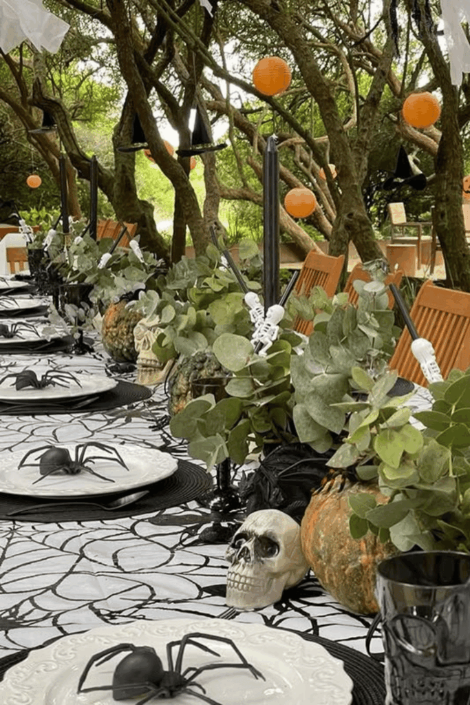 Outdoor Halloween tablescape with skulls, spiders, and greenery