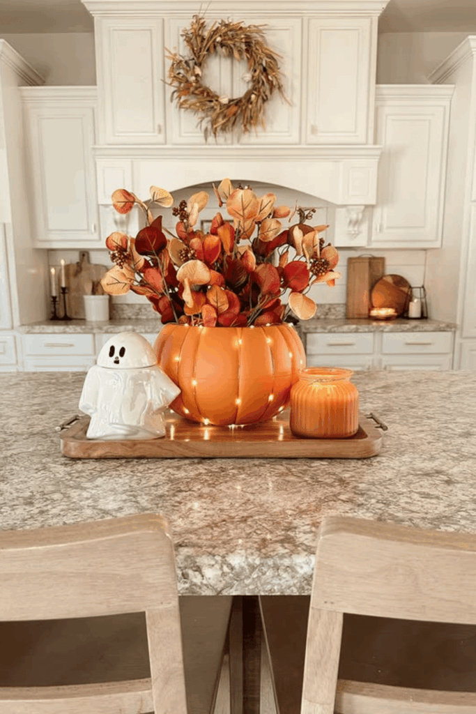 Pumpkin vase filled with colorful fall flowers on a center island