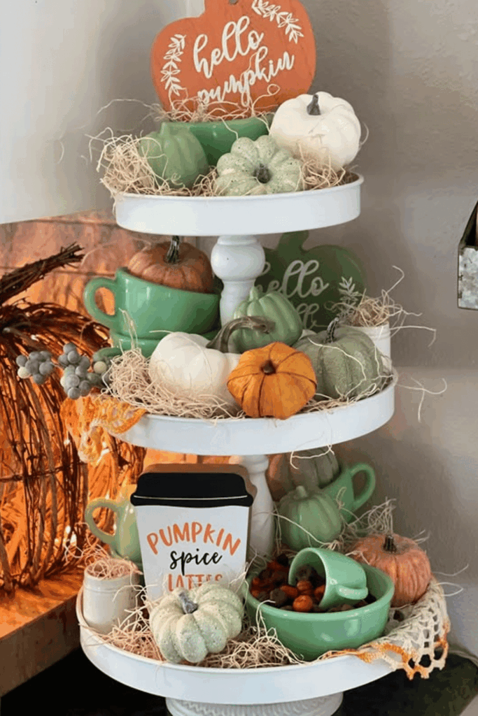Tiered tray decorated with small pumpkins, mugs, and fall accents