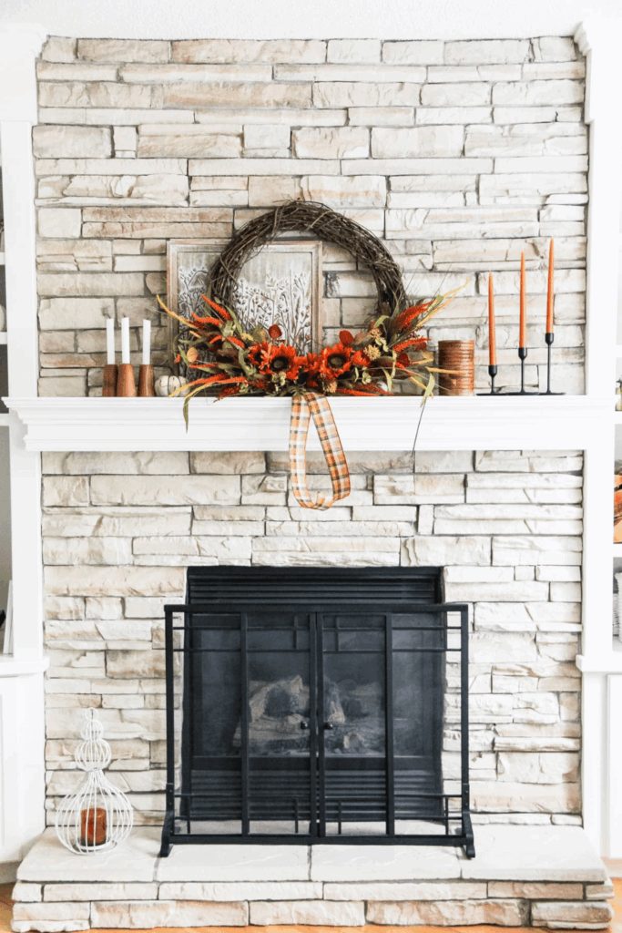 Grapevine wreath and black candlesticks on rustic fall mantel