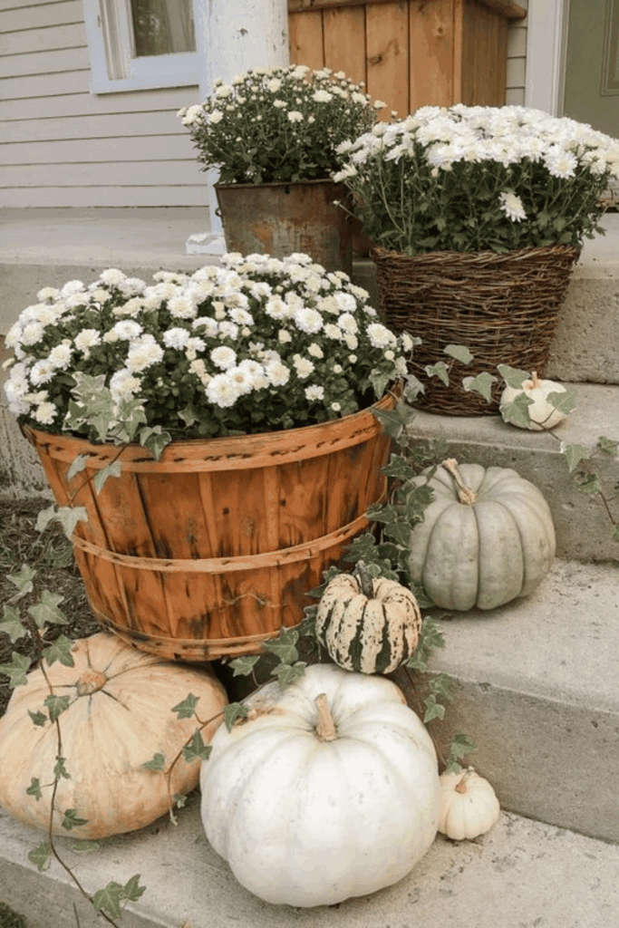 White chrysanthemums and pale pumpkins in rustic baskets on front porch