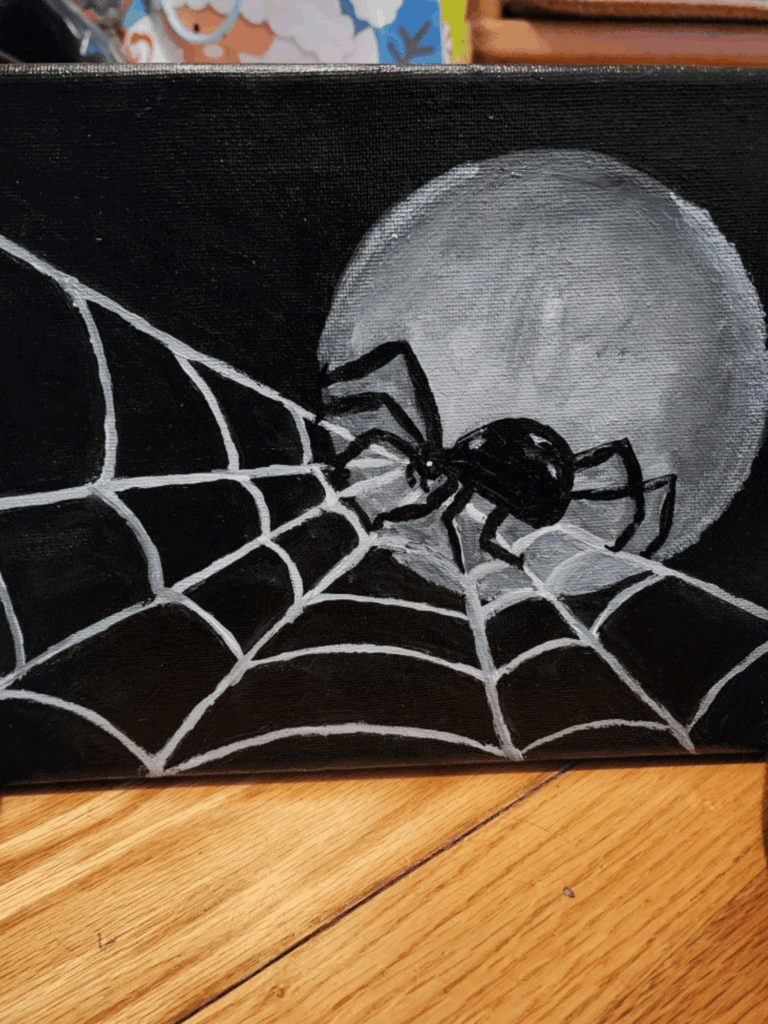 Black spider spinning web in front of full moon