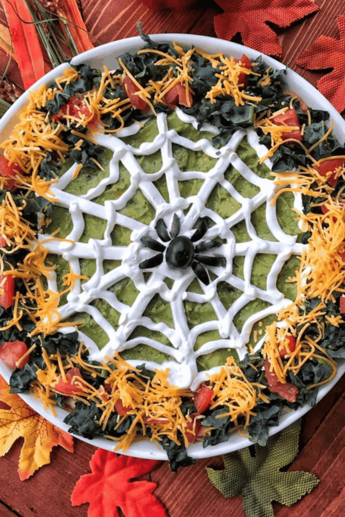 Spider web taco dip topped with sour cream spider web and black olives