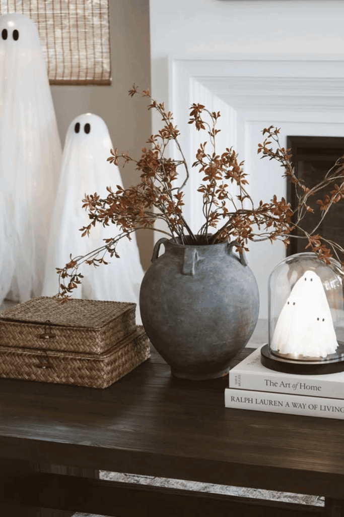 Subtle Halloween coffee table vignette with ghost figurines and cloche