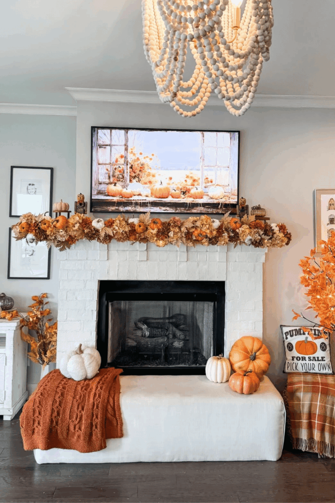 White brick fireplace mantel decorated with pumpkins, orange garland, and fall colors.