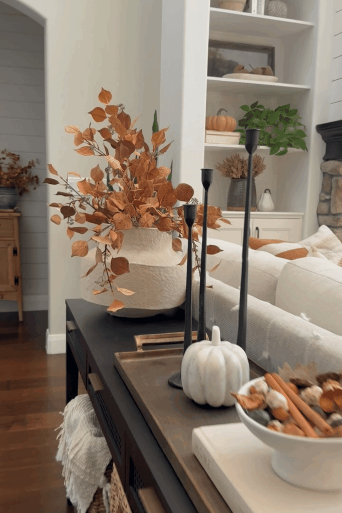Neutral living room with a vase of autumn branches on a console table and soft accents.