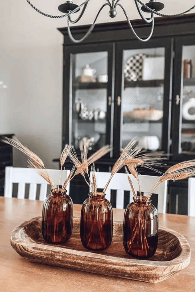 Amber glass jars filled with wheat and dried grasses on fall table