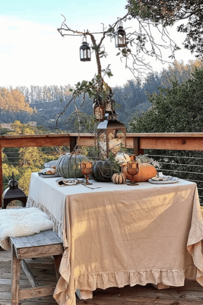 Outdoor fall table with pumpkins, lanterns, and branches