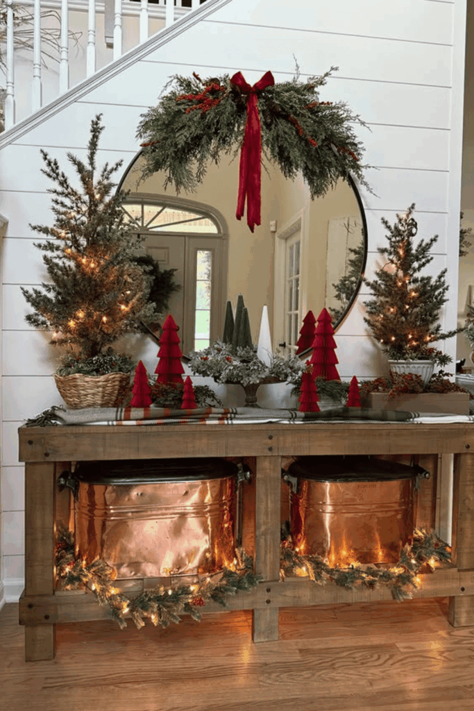 Entry console decorated with mini trees, red accents, and Christmas greenery
