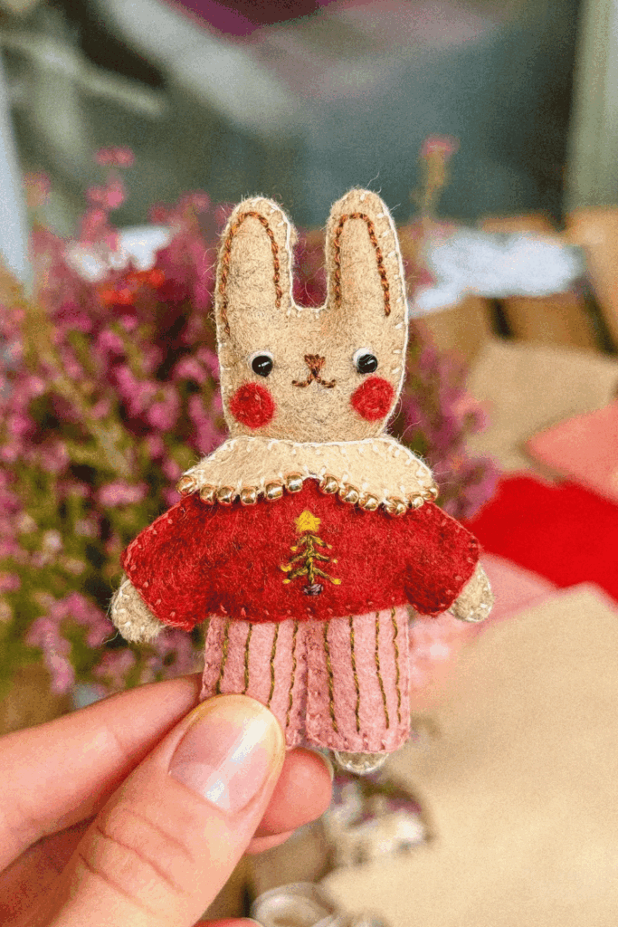Hand-sewn felt bunny ornament wearing a red and pink outfit