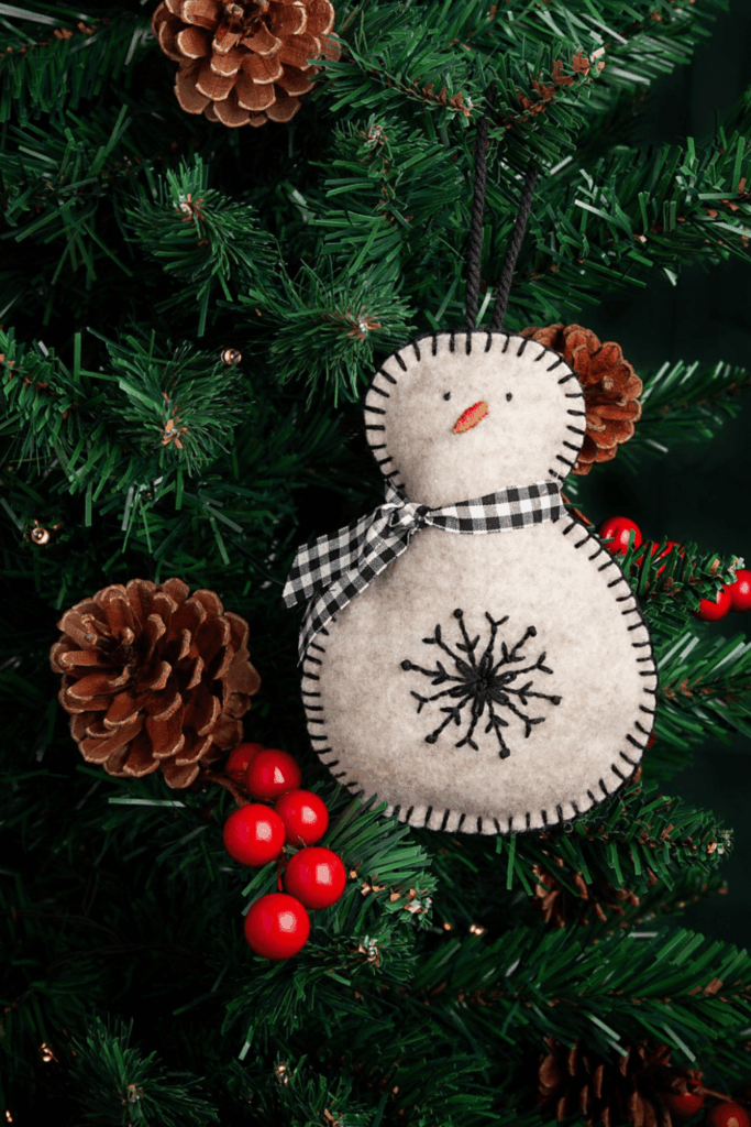 Cozy felt snowman ornament with stitched snowflake and gingham scarf