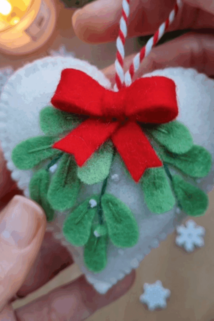 White felt heart ornament decorated with layered felt mistletoe and red bow