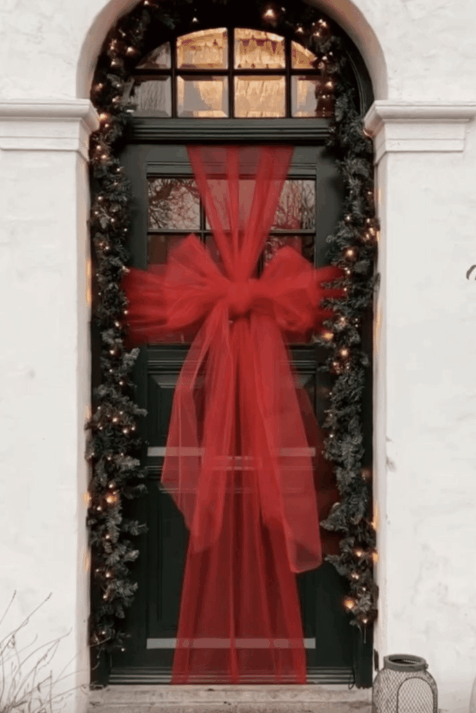Front door wrapped like a Christmas gift with big red bow outdoor Christmas decorations