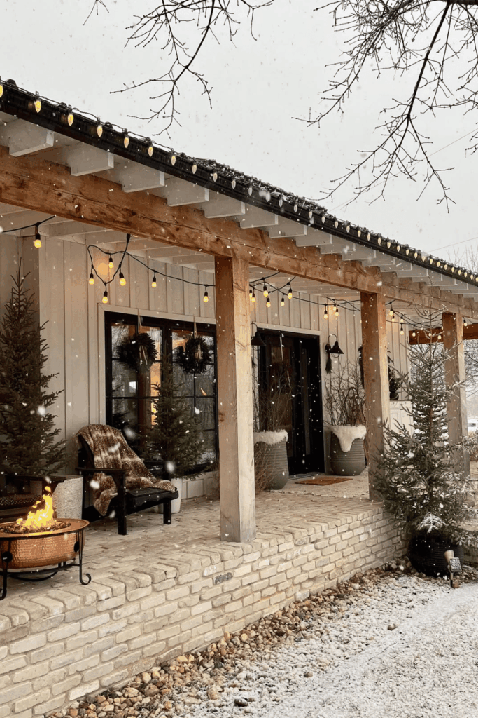 Nordic style porch with snow-covered evergreens and amber lights