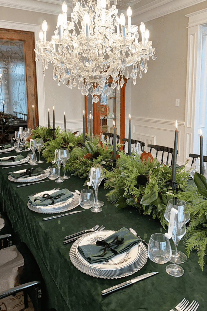 Green tablecloth with lush greenery centerpiece on a Christmas dining table