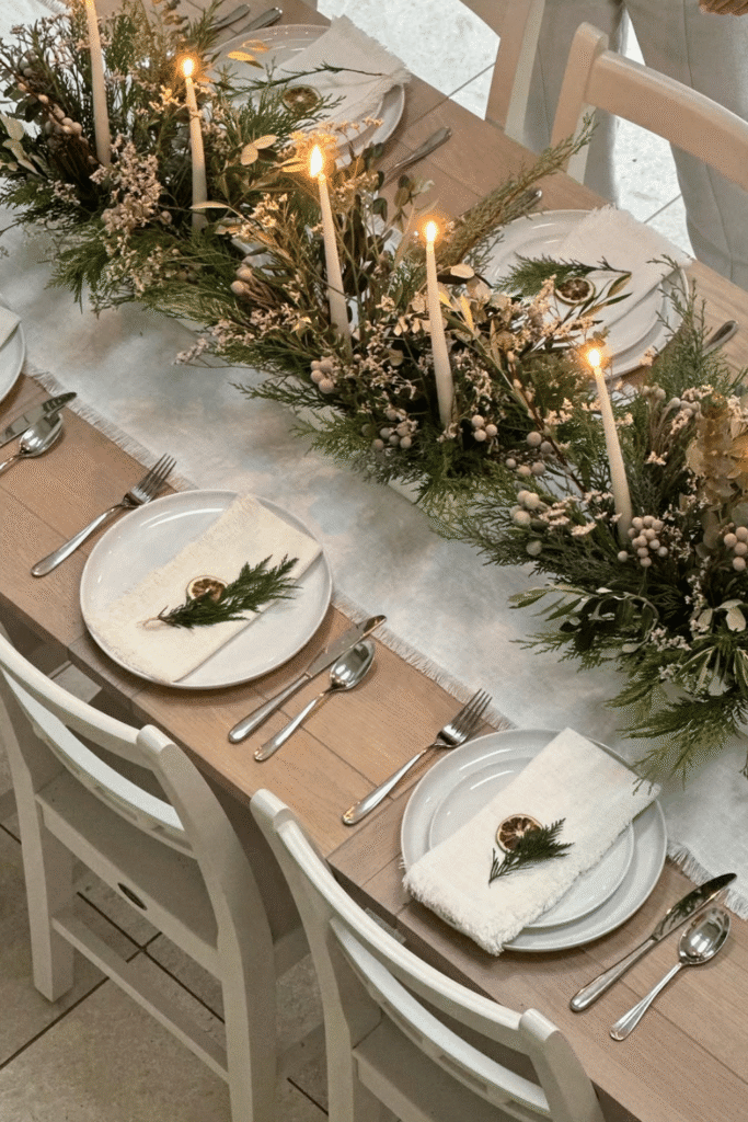 Neutral Christmas table setting with white linens and simple greenery runner