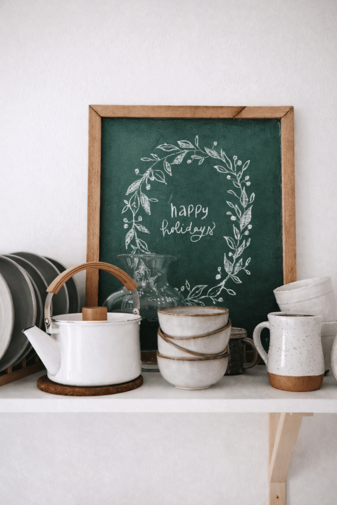 Happy holidays chalkboard sign with wreath design on kitchen shelf
