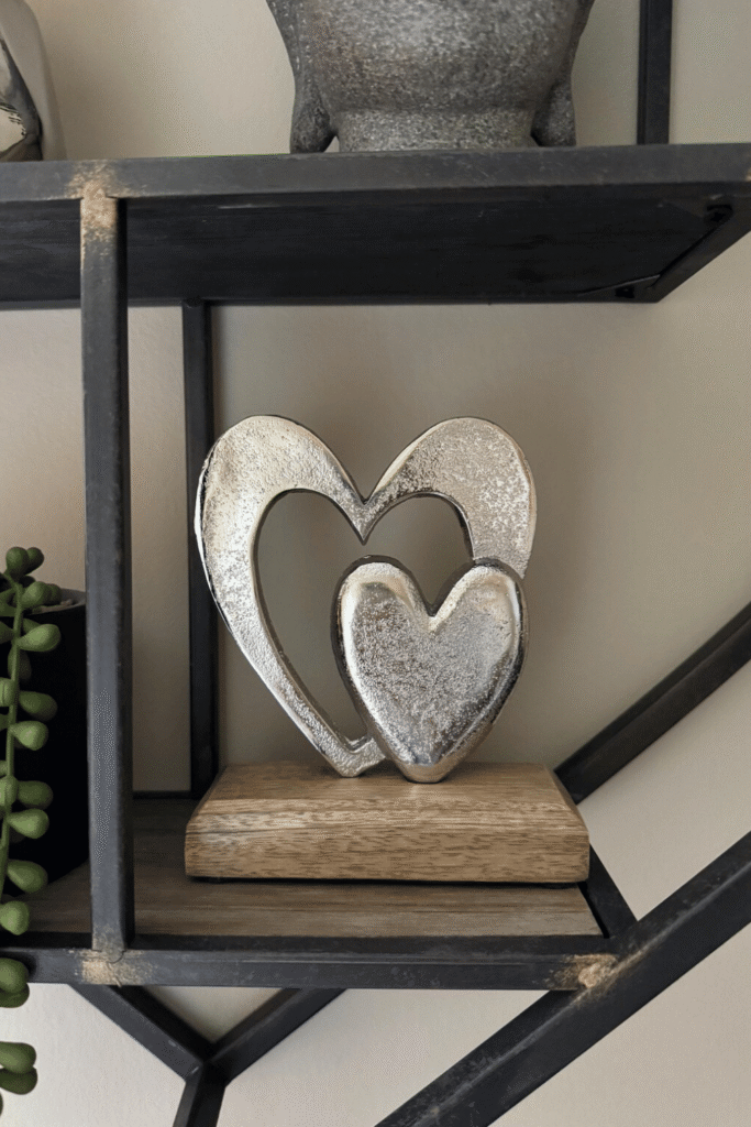 Sculptural silver heart decor on wooden shelf