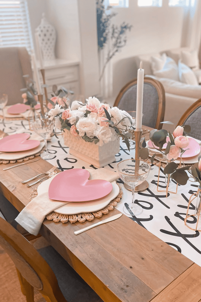 Modern Valentine’s table with script table runner, pink flowers, and heart plates