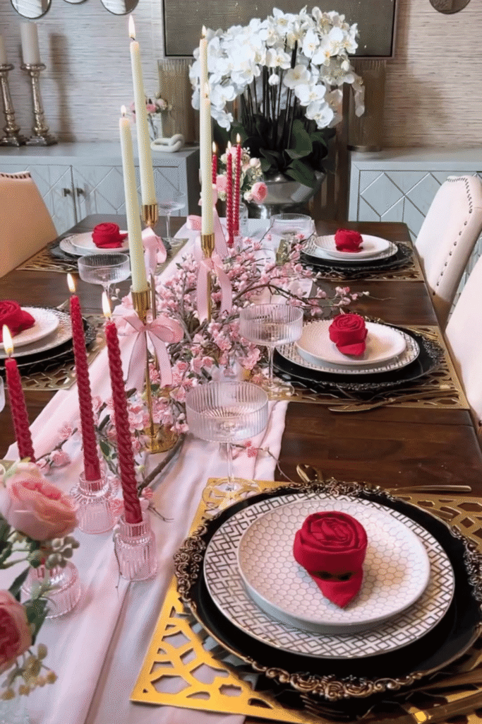 Romantic Valentine’s table with gold accents, layered plates, and pink floral centerpiece