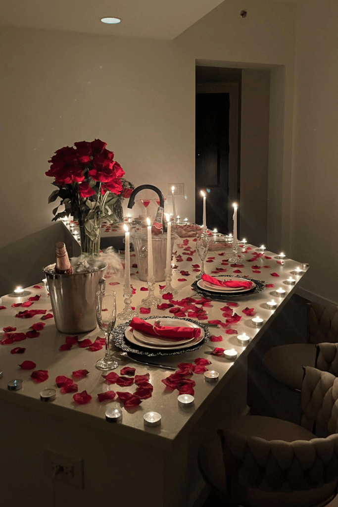 Dramatic Valentine’s dinner table with rose petals, candles, and red roses