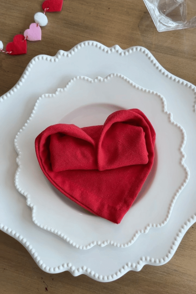 Valentine’s place setting with heart-shaped napkin folded on white plates